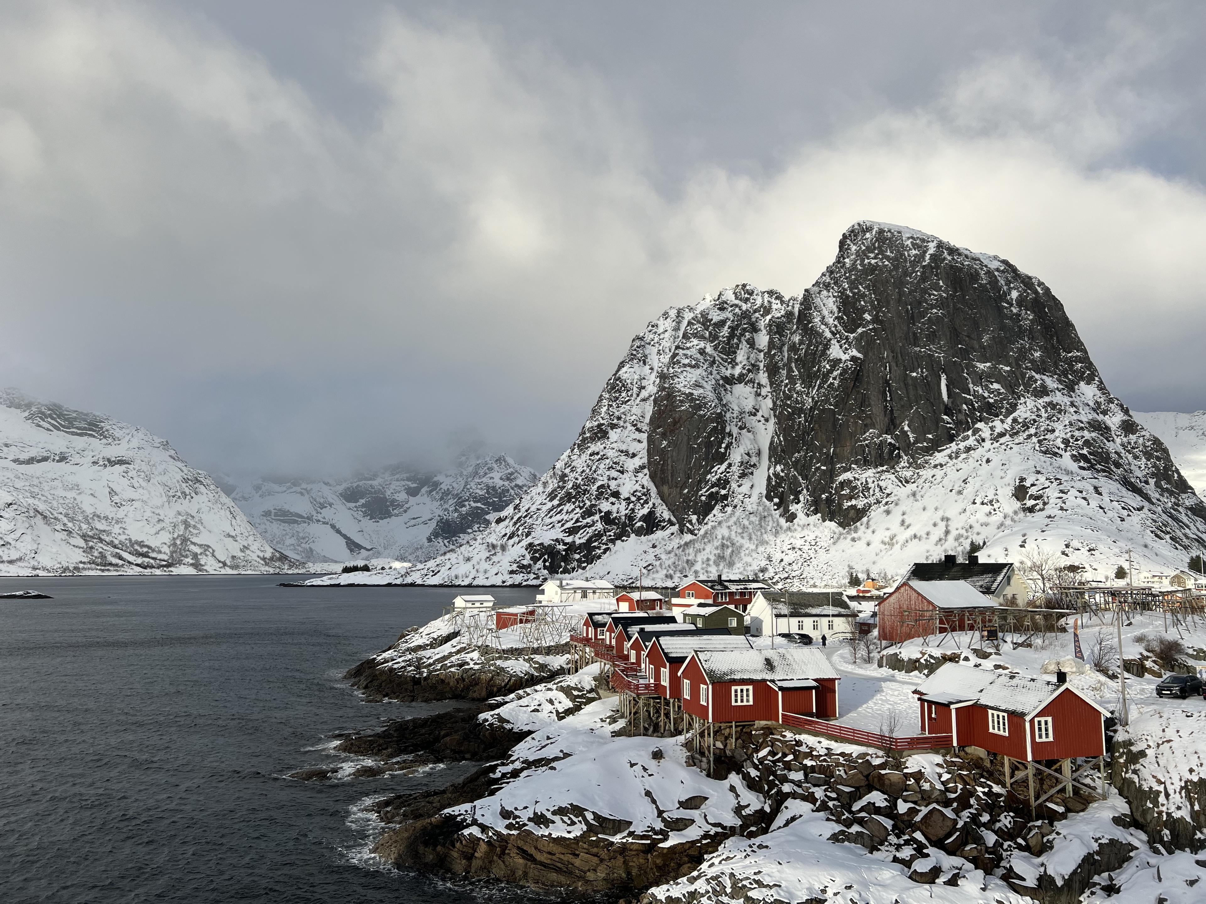 Red cabins under a snowy mountain by the sea