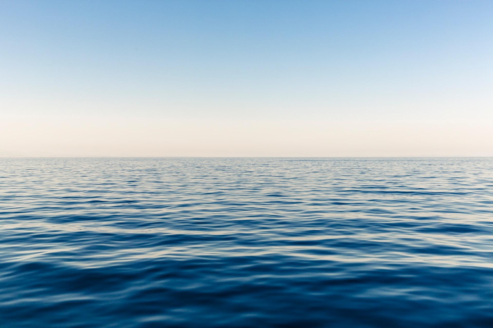 Calm open ocean under a hazy sky